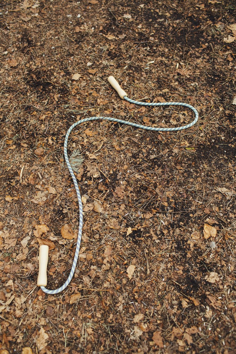 Corde à sauter posée sur un sol de terre et de feuilles