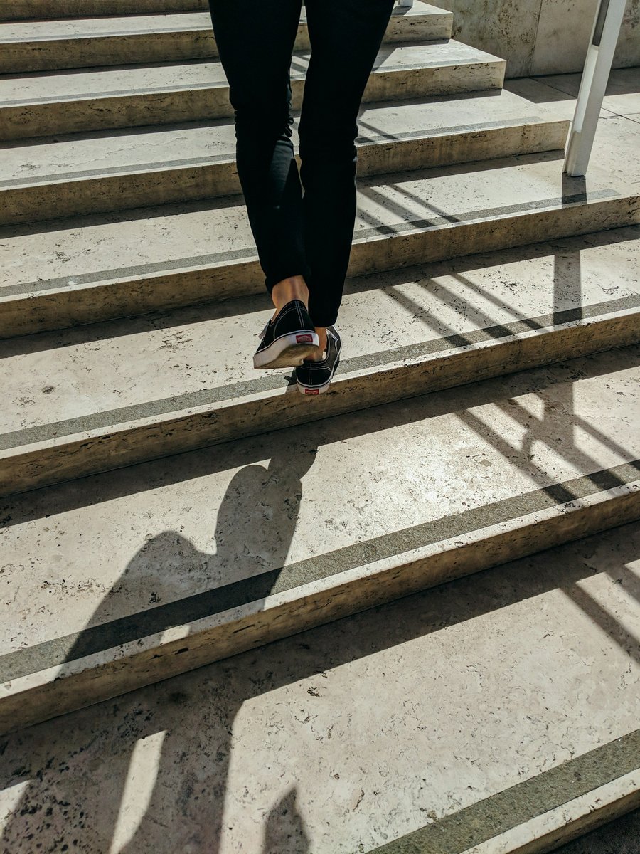 Jambes descendant un escalier de pierre au soleil