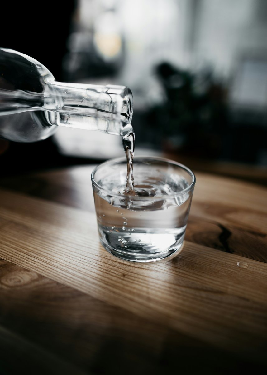 Eau versée dans un verre posé sur une table en bois
